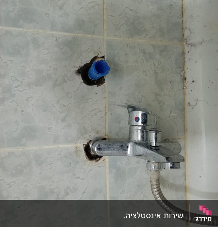 ברז מים מותקן על קיר עם צינור גמיש